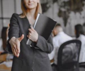 Woman in a suit holds a folder.