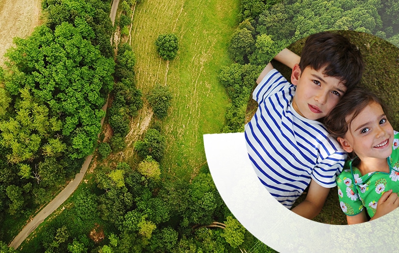 Clairière et arbres vu du ciel avec 2 enfants allongés à droite