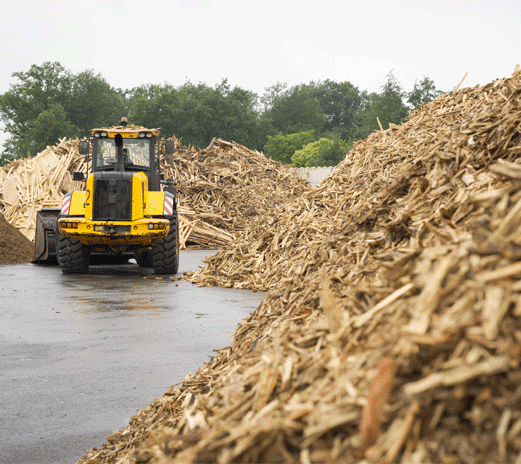 Tractopelle avec des piles de copeaux de bois